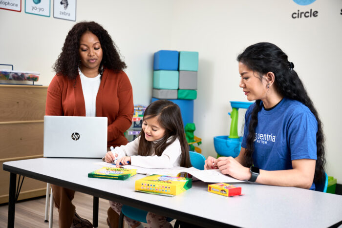 a child, behavior technician and bcba sitting at a table