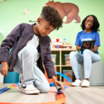 young boy playing with cars with a behavior technician