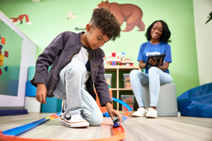 young boy playing with cars with a behavior technician