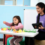 young girl playing with flower toys by behavior technician