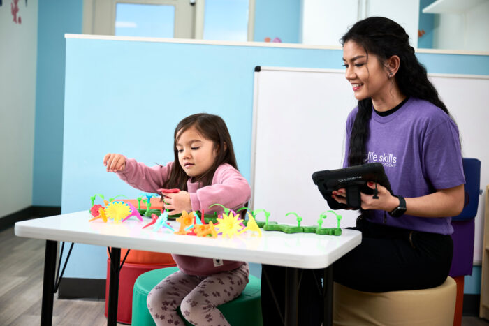 young girl playing with flower toys by behavior technician