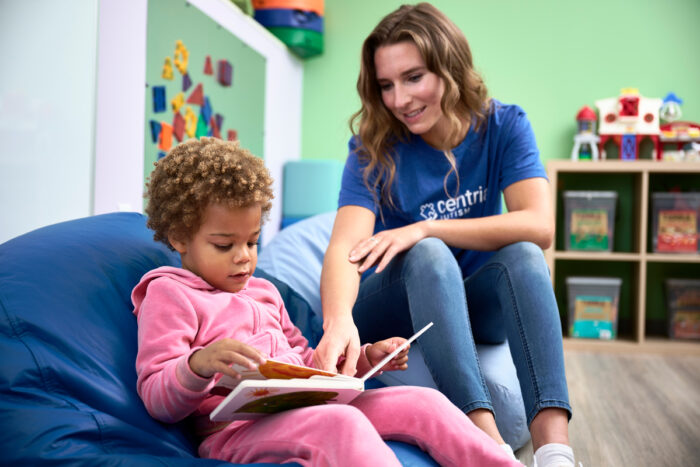 girl and behavior technician reading a book